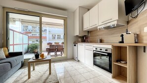 Une cuisine compacte dotée d’un four encastré, un coin repas avec une table et des chaises, et un canapé.