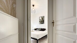 Une chambre à coucher avec un lit, un luminaire fixé au mur et un tableau encadré.
