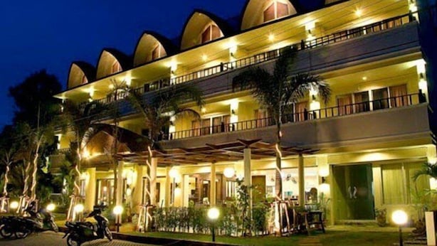 Un hôtel à plusieurs étages, doté d’une façade symétrique, de nombreux balcons et d’un hall d’entrée bien éclairé.
