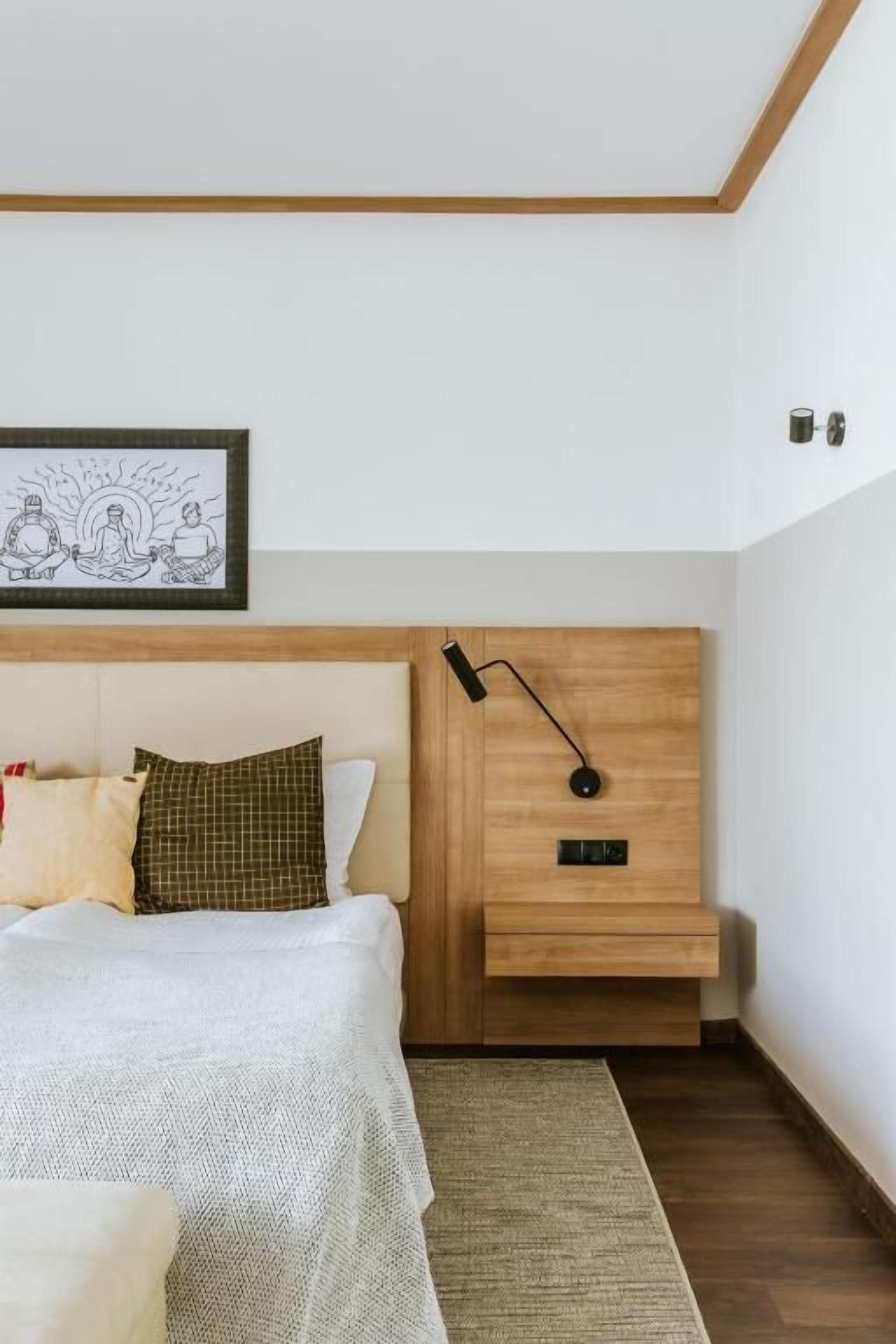 A bedroom with a wooden headboard, a bedside table with a lamp, and a framed artwork above the bed.