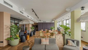 A spacious lounge area with seating, potted plants, and a modern ceiling design. -  WorkNomads LAB Hotel-Coliving & Coworking (Sofia)