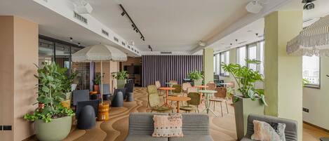 A spacious lounge area with seating, potted plants, and a modern ceiling design.