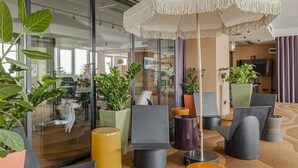 A modern lobby with black chairs, a large umbrella, and potted plants. -  WorkNomads LAB Hotel-Coliving & Coworking (Sofia)