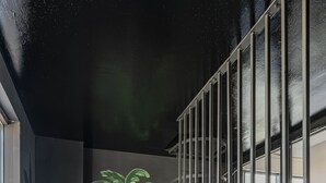 A staircase with a metal railing, a mural of tropical plants on the wall, and a window with a view of the outside. -  WorkNomads LAB Hotel-Coliving & Coworking (Sofia)