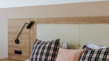 Una cama con cabecera, dos almohadas y una manta.