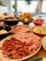 A table with various food items including sliced meats and vegetables.