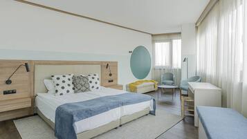 Een moderne hotelkamer met een groot bed, nachtkastjes, een bureau, een stoel en een bank.