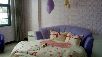 A bedroom with a bed, a nightstand, a lamp, and a window with curtains.