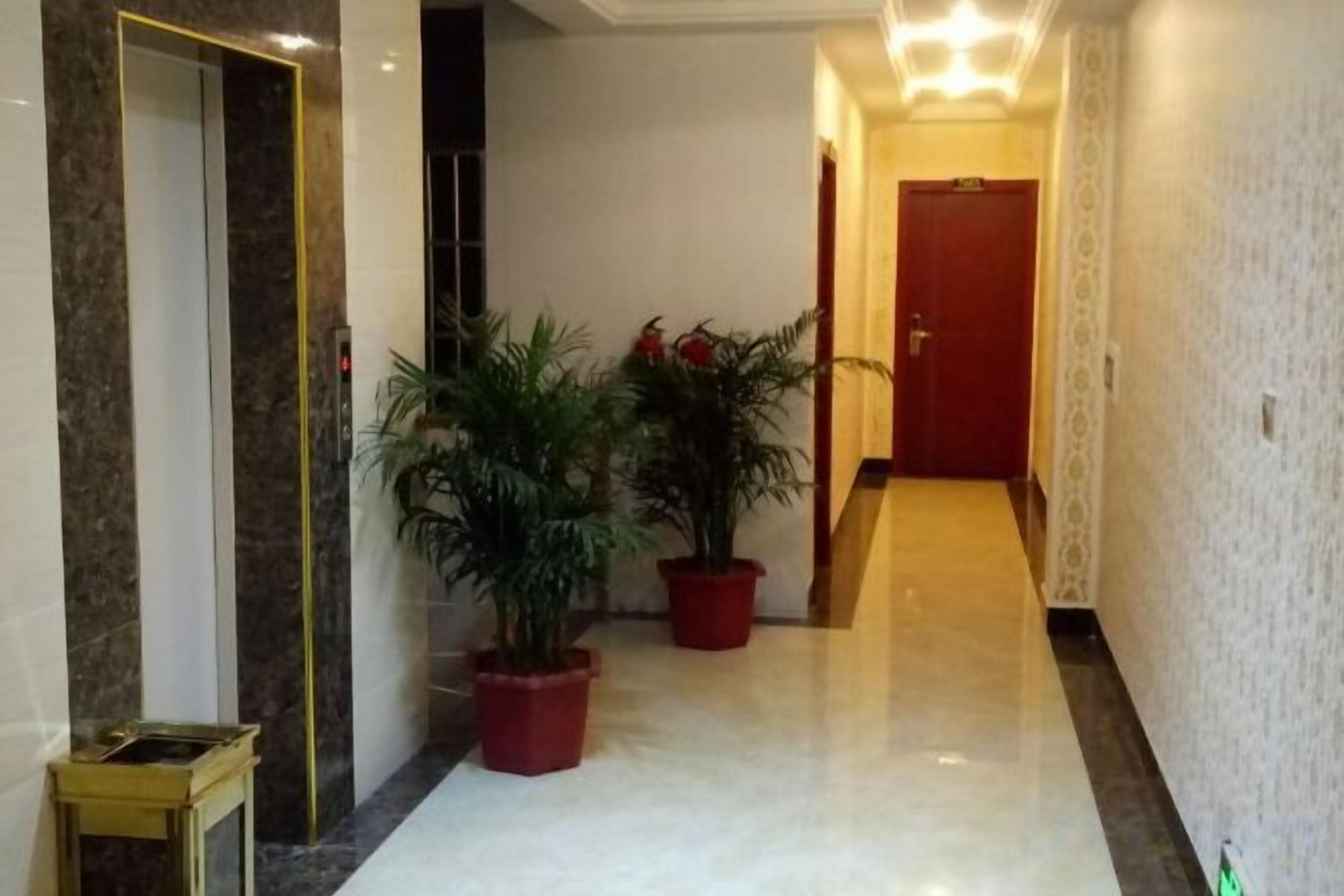A hallway with marble flooring, potted plants, and a door at the end.