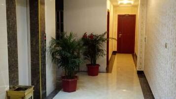 A hallway with marble flooring, potted plants, and a door at the end.