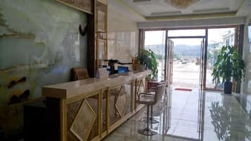 A reception area with a marble counter, bar stools, and a large potted plant.