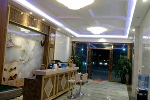 A hotel lobby with a reception desk, seating area, and a large plant. - Yuanmengyuan Hotel (Guangnan)
