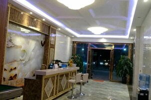 A hotel lobby with a reception desk, seating area, and a large plant.