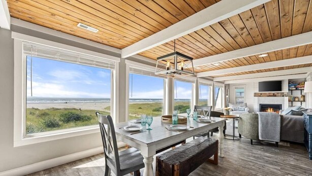 A spacious dining area with a view of the beach, a fireplace, and a cozy seating area with a television. - 100 Steps to the Beach, Amazing Views and Sunsets (Moclips)