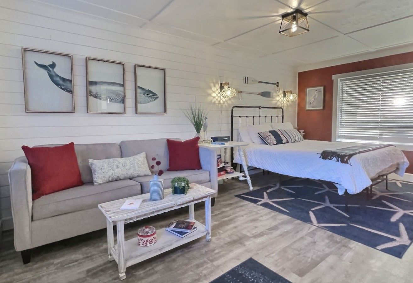 A cozy living room with a sofa, coffee table, and a bed with a star-patterned rug.
