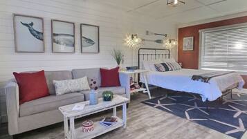 A cozy living room with a sofa, coffee table, and a bed with a star-patterned rug.