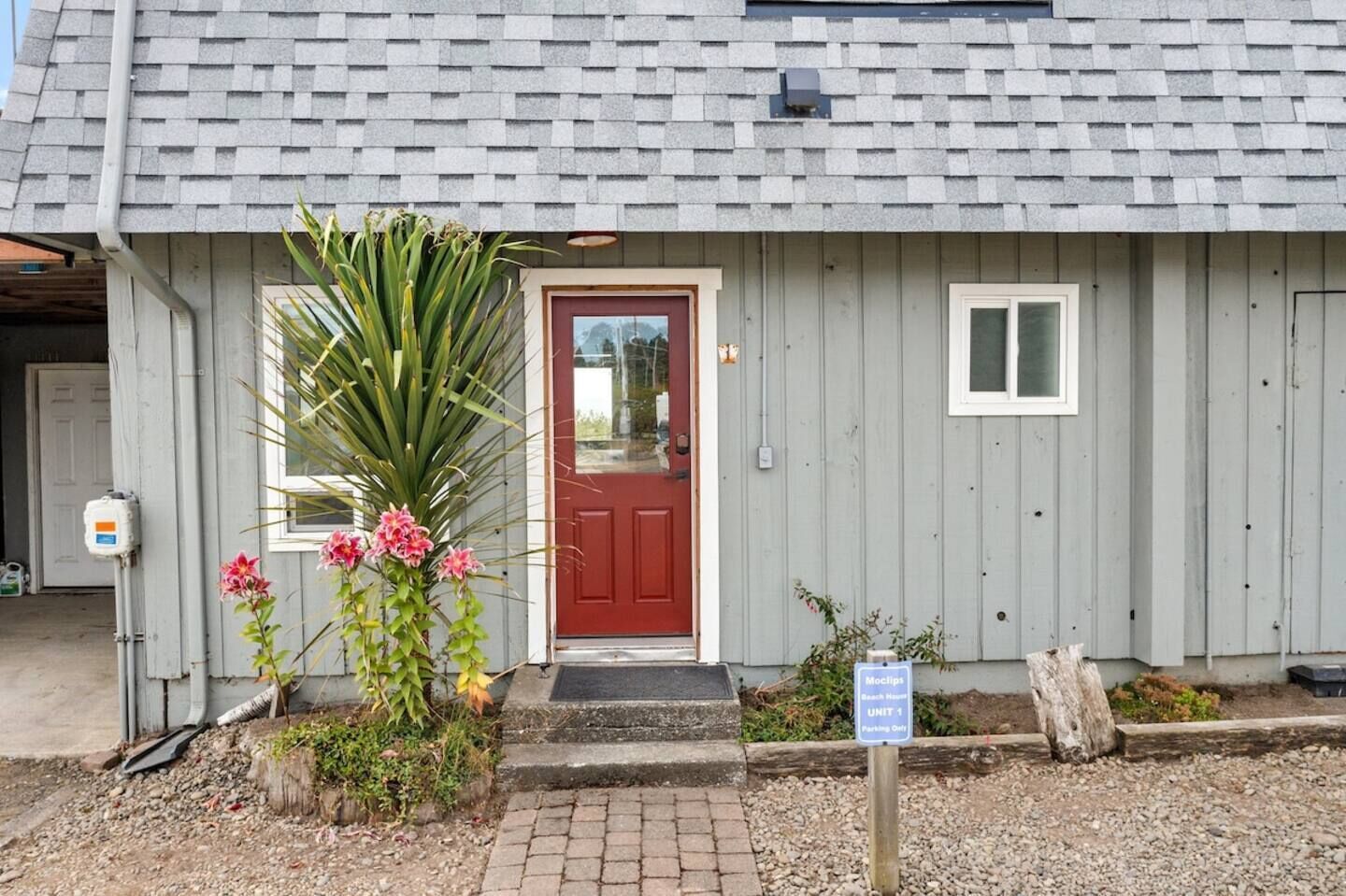 A small building with a red door, a small window, and a sign indicating a parking area.