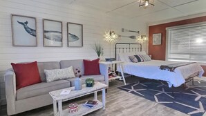 Una sala acogedora con un sofá, una mesa de centro, una cama y un ventanal con persianas.