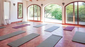 A yoga studio with multiple mats laid out on a tiled floor, large arched windows, and a view of greenery outside. - nowenqew;PIHFR' (Cunit)
