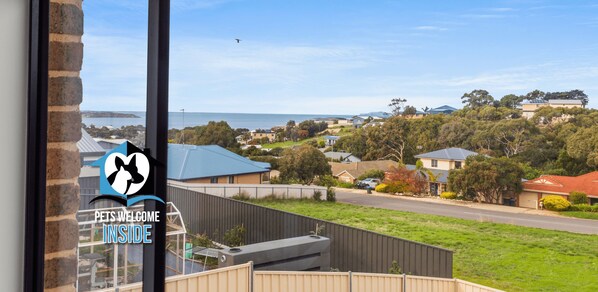 A residential area with houses, a clear sky, and a view of the sea.