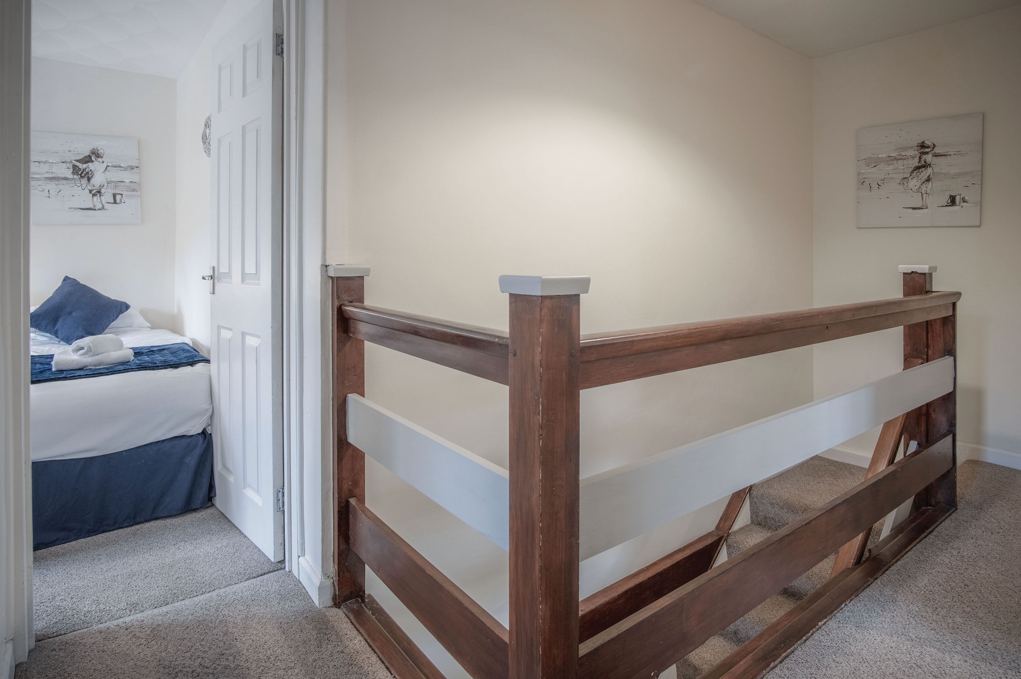 A bedroom with a wooden bed frame, a white door, and a blue pillow.