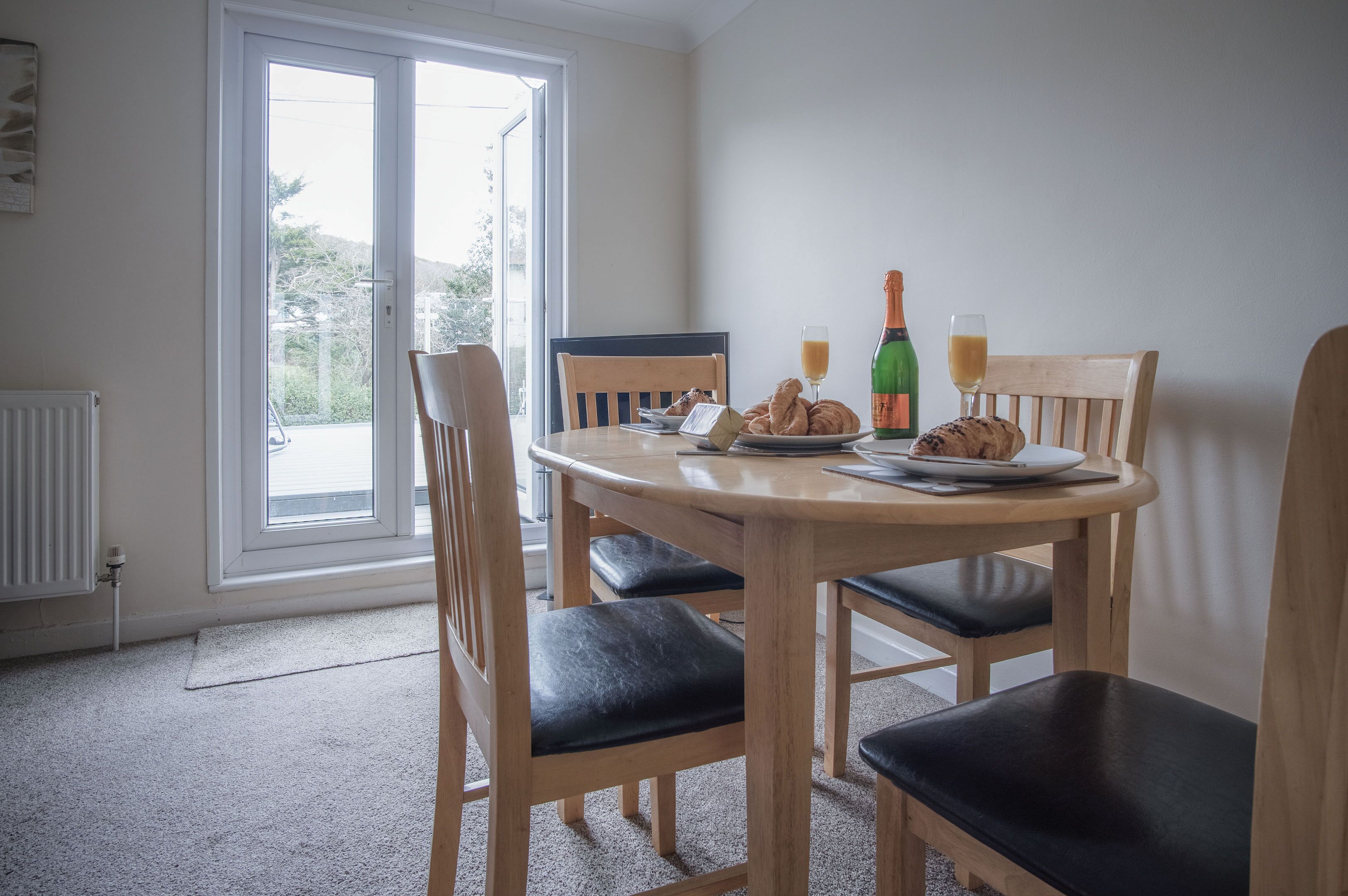 Een eetgedeelte met een ronde tafel, vier stoelen, een raam en een radiator.