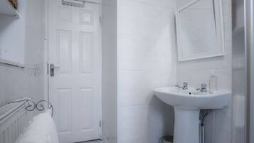 Un baño con una puerta blanca, un lavabo y un perchero para toallas.
