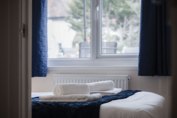 Quarto com cama, janela e radiador.