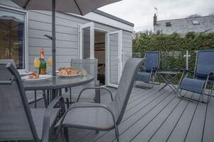 Un patio al aire libre con una mesa dispuesta para el desayuno, incluyendo cruasanes y jugo, además de una botella de champán.