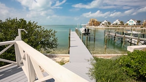 A wooden pier extending into clear turquoise water, leading to a dock with boats. - Shore Leave – Relax, Unwind & Enjoy Paradise in Style (Elbow Cay)