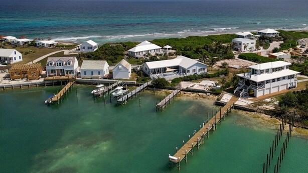 An aerial view of a coastal property with multiple houses, a dock, and a marina. - Shore Leave – Relax, Unwind & Enjoy Paradise in Style (Elbow Cay)