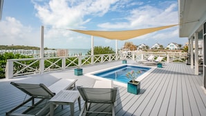 A deck with a pool, lounge chairs, and a view of the sea and houses in the background. - Shore Leave – Relax, Unwind & Enjoy Paradise in Style (Elbow Cay)