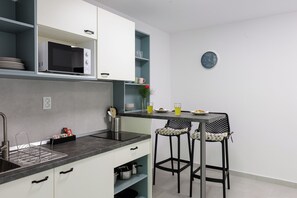 A modern kitchen with a built-in microwave, a sink, and a dining area with two bar stools.