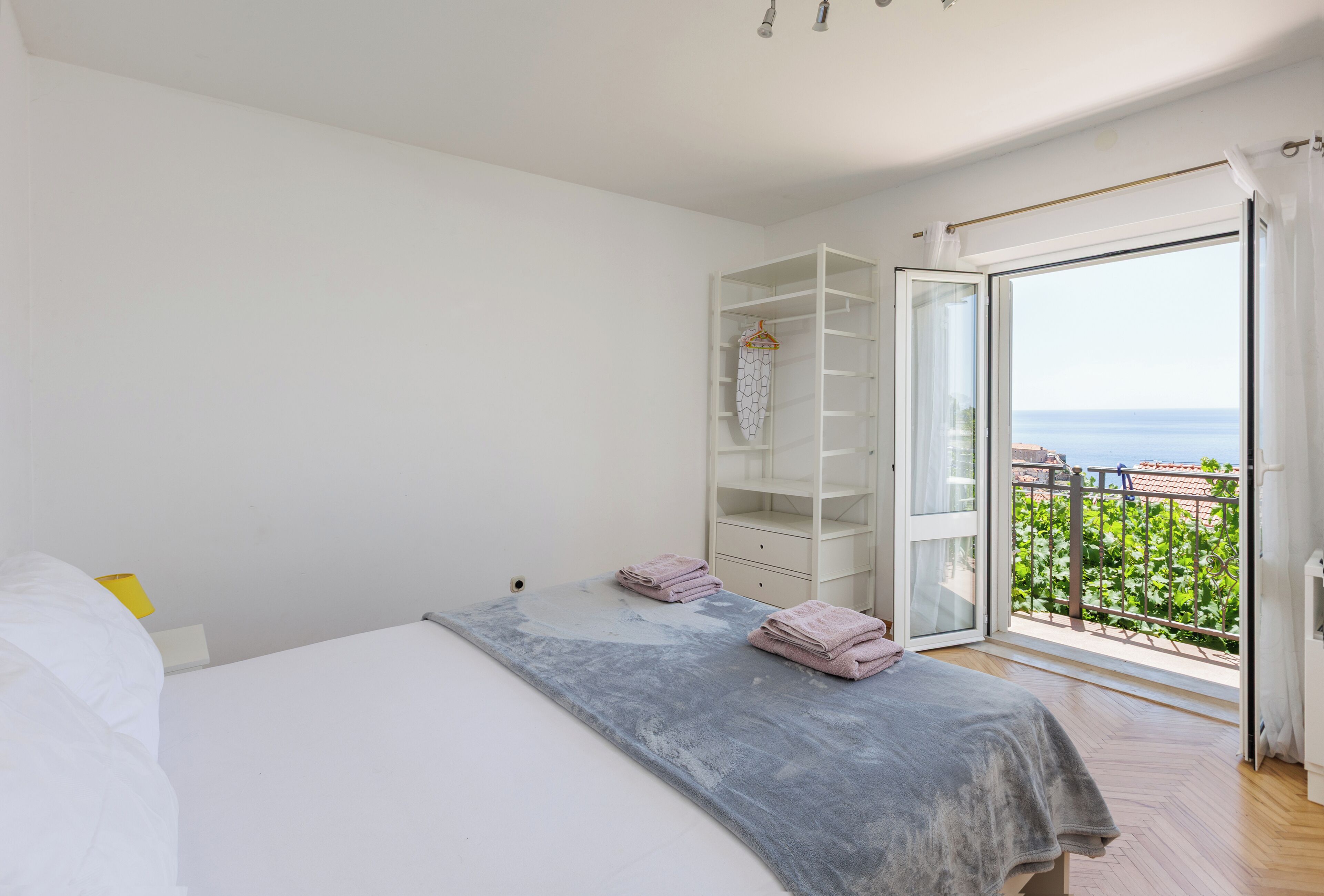 Un dormitorio con cama, armario y balcón con vistas.