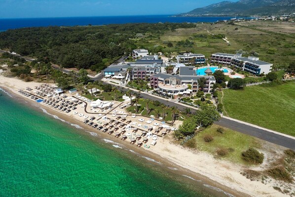 An aerial view of a resort with a beach, multiple buildings, and a pool area. - Ilio Mare Beach Hotel by GHH (Thasos)