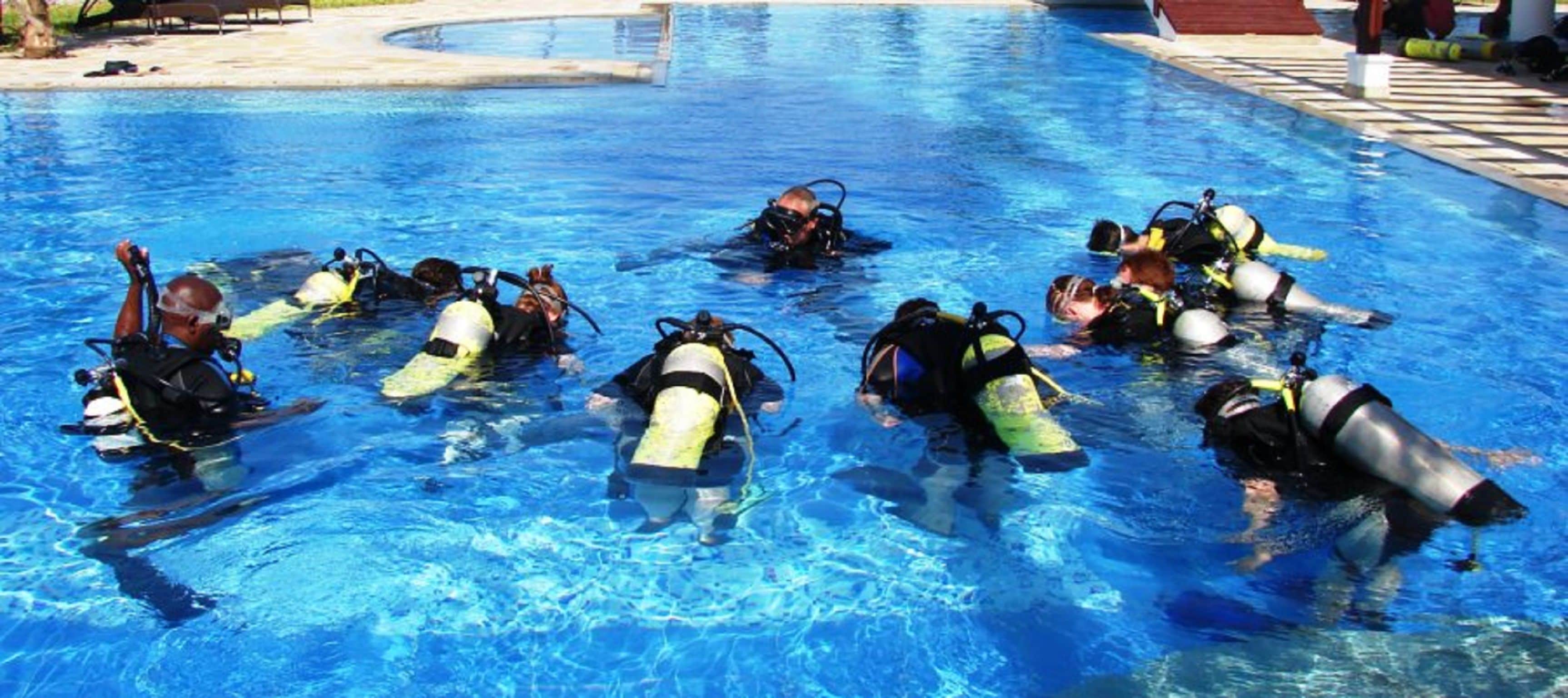 A group of people in a swimming pool wearing scuba diving gear.