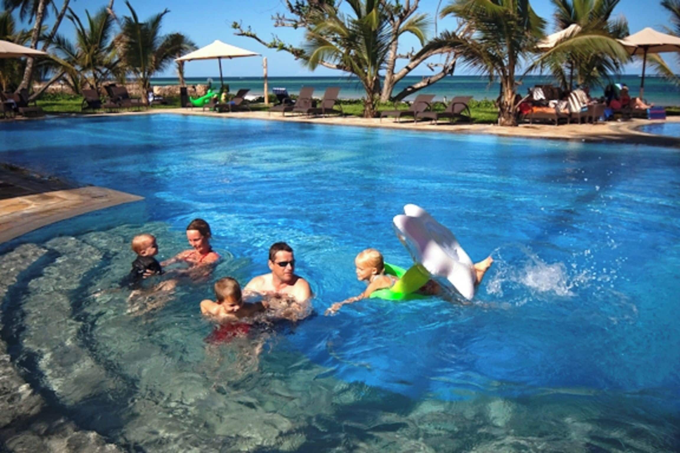 Una piscina con gente y un flotador con forma de delfín.