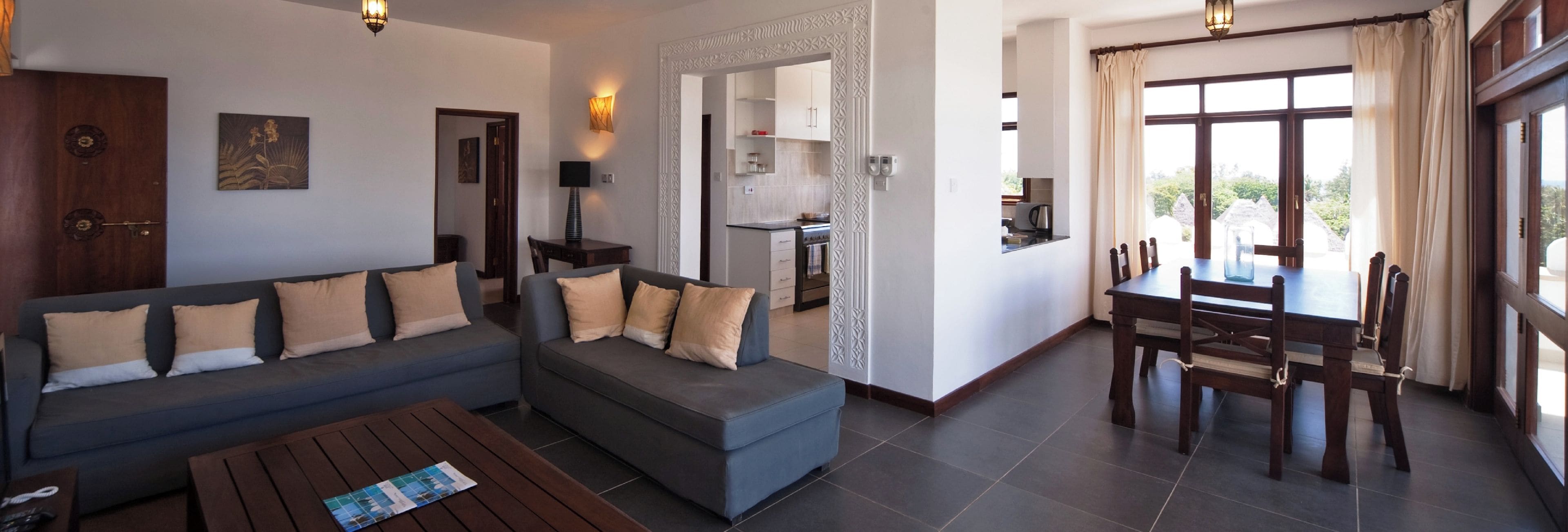 A modern living room with a sofa, coffee table, and dining area with chairs.