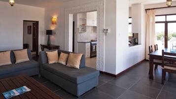 A modern living room with a sofa, coffee table, and dining area with chairs.