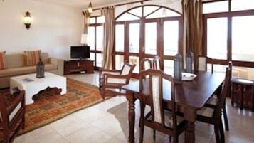 A living room with a sofa, coffee table, TV, and dining area with chairs and a table.