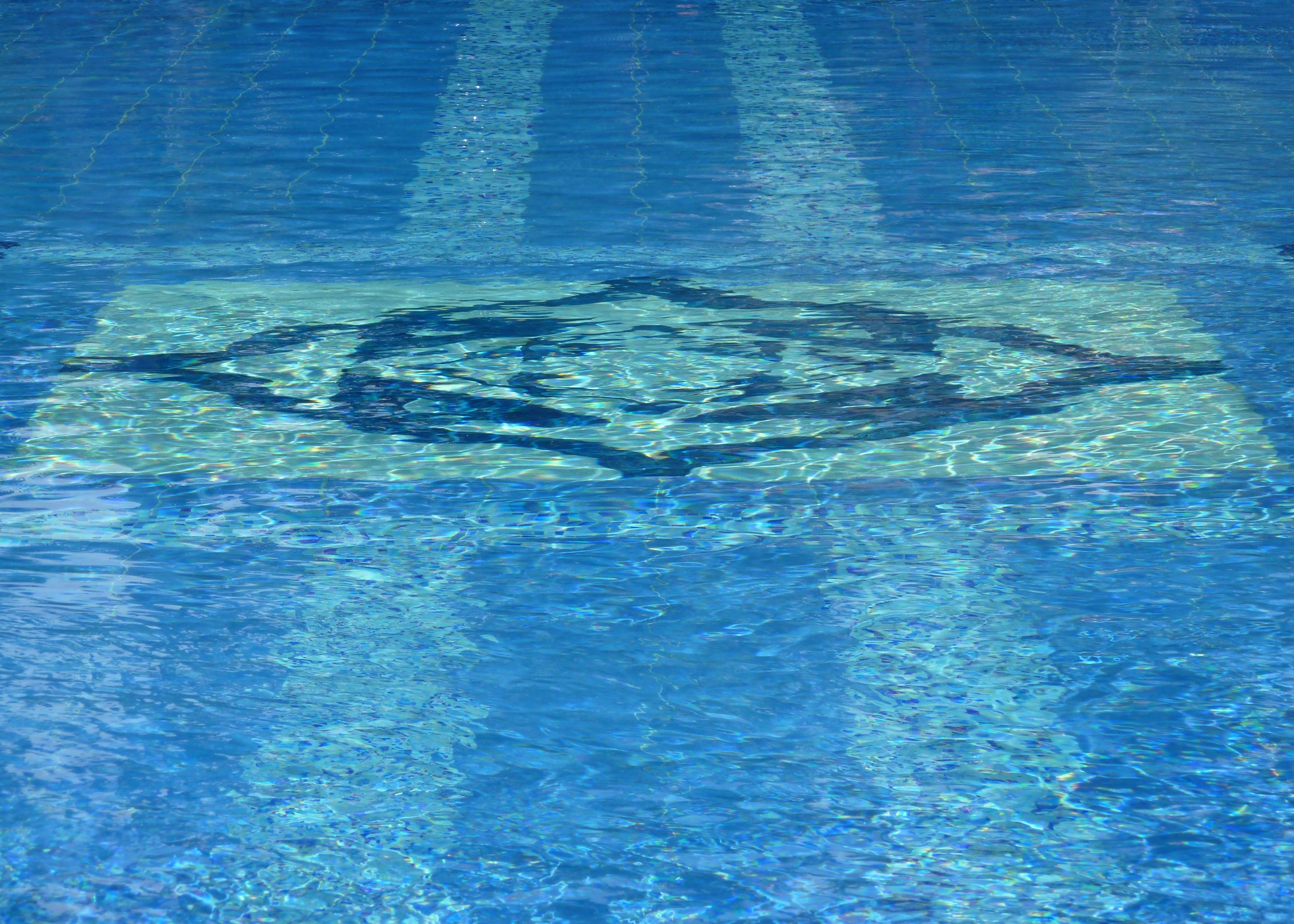 A clear blue pool with a geometric pattern on the floor.