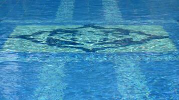 A clear blue pool with a geometric pattern on the floor.
