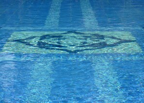 Una piscina azul cristalina con un diseño geométrico en el fondo.