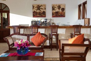 A living room with a coffee table, chairs, a sofa, and a bar area with a coffee machine. - Lantana Galu Beach (Diani Beach)