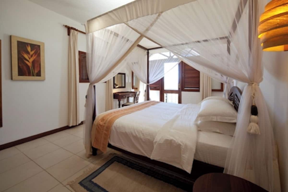 A bedroom with a canopy bed, a desk, and a chair.