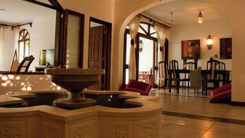 A lobby with a fountain, a dining area, and a view of the outside.