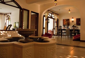A lobby with a fountain, a dining area, and a view of the outside. - Lantana Galu Beach (Diani Beach)