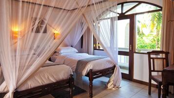 A bedroom with a canopy bed, a wooden chair, and a view of greenery outside.