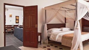A four-poster bed with a canopy, a wooden door, and a view of the sea. - Lantana Galu Beach (Diani Beach)
