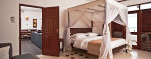 Una cama con dosel y cortina, una puerta de madera y vistas al mar.
